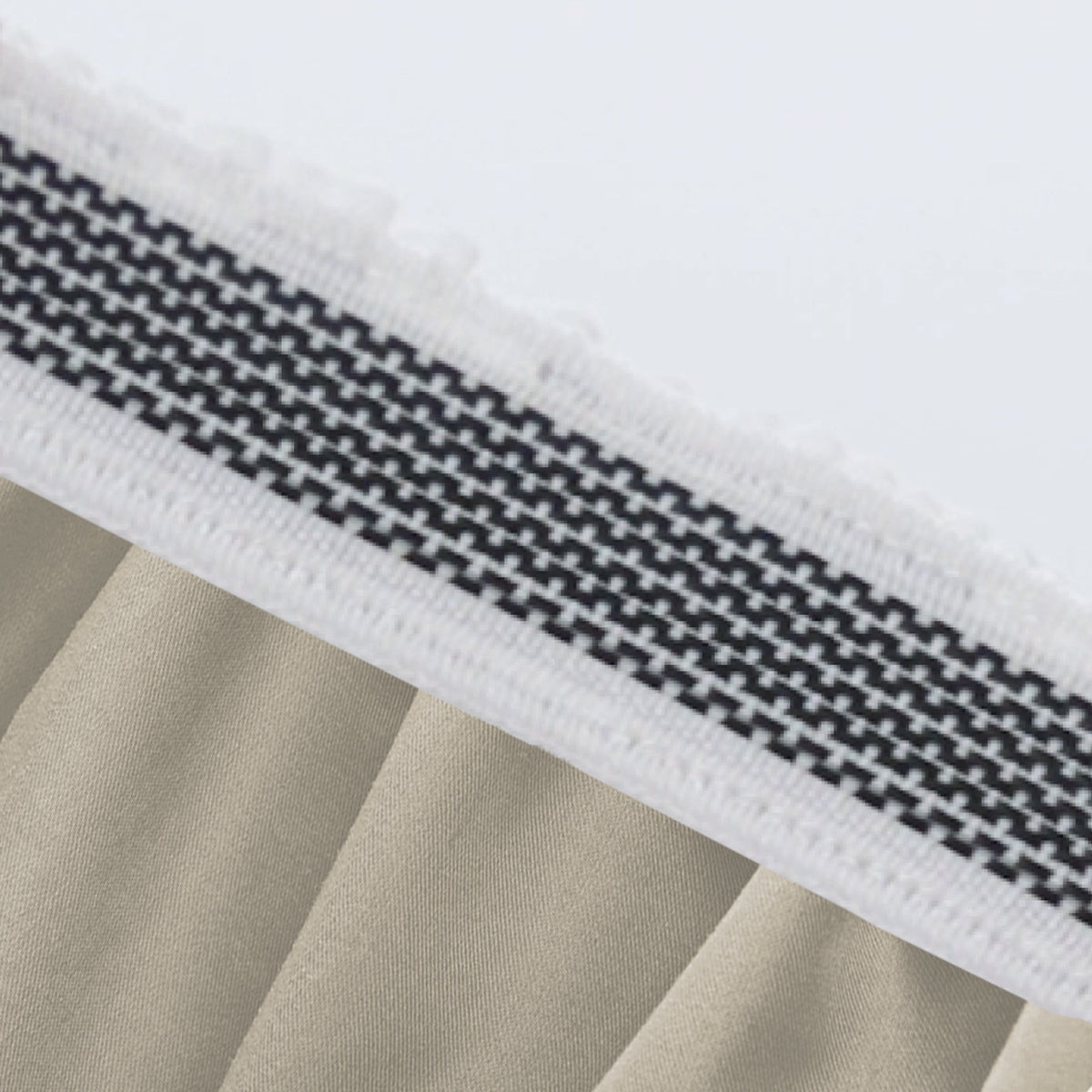 Close-up of thick, patterned elastic band on beige Egyptian Cotton Sateen deep-pocket fitted sheet.