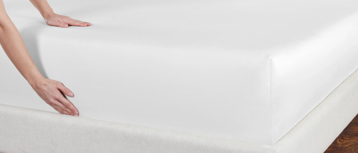 Beautifully made bed with a smooth fitted sheet in morning light