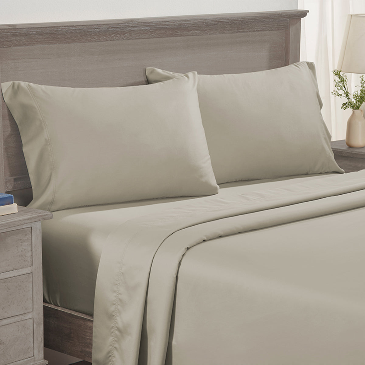 Bed made with smooth beige Egyptian Cotton Sateen sheets and a wooden headboard for luxury comfort.