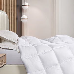 Soft white quilted down alternative comforter and white duvet cover in a neutral setting bedroom.